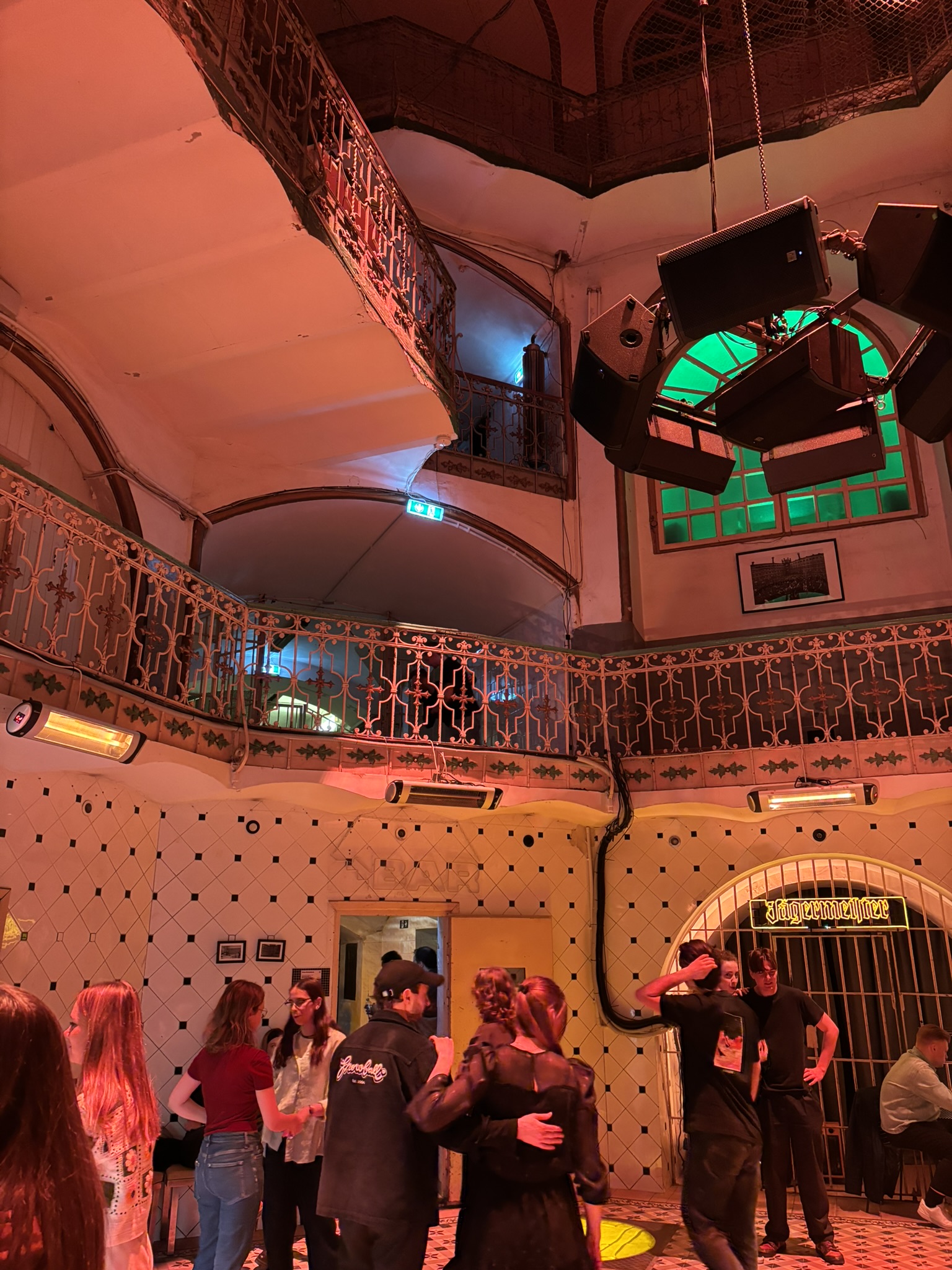People socialising inside Lukiškės Prison 2.0 with colourful lighting and balconies