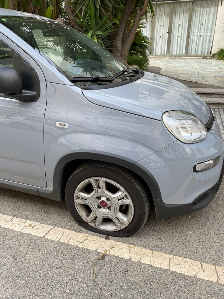 Flat tyre on a grey rental car parked on a street in Salou, Spain